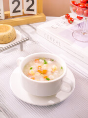 Fresh Corn Kernel Vegetable Soup in White Cup with Cheese and Tomatoes on Wooden Table