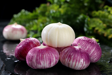 Fresh Purple and White Garlic Bulbs with Water Drops on Dark Surface