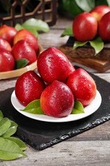 Fresh Red Nectarines from Dalian China on Rustic Wooden Table with Water Droplets and Green Leaves