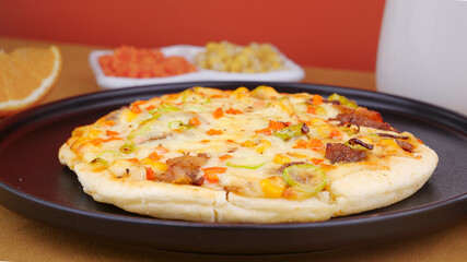 Fresh homemade pizza with bacon and vegetables on dark plate - delicious Italian food photography