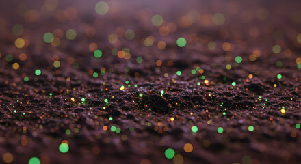 Mysterious glowing green and orange particles scattered across a dark, textured landscape with a shallow depth of field