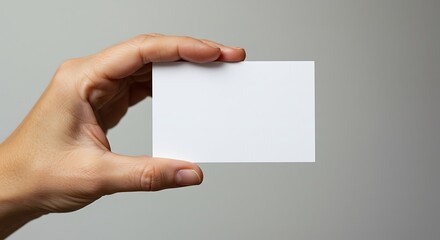 Obraz premium Hand holding blank business card against neutral background for mockup