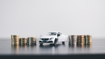 White car model with open door surrounded by stacked coins, symbolizing auto loan, car finance,...