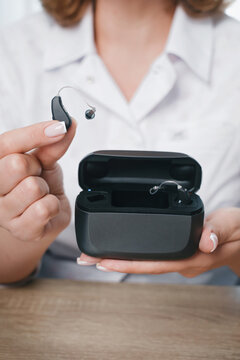 Patient charging hearing aid in special portable Smart Charger with built-in power bank. Case in man hands keeps hearing aids dry and safe