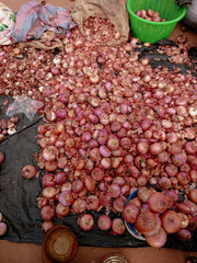 Selling group of onions arranged on street ground at local market in Kumasi, Ghana. African market arrangement and setup. Onions in sacks and basket.