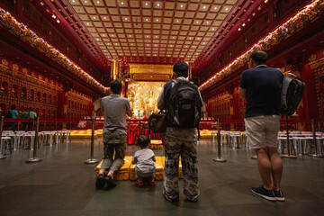 Naklejka premium On September 24, 2018, inside a grand temple in Singapore, the main hall glows with golden Buddha statues, ornate decorations and rows of offerings, embodying devotion, peace, and sacred spirituality.
