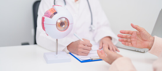 Elderly Patient consulting Doctor to Eye disease, Senior Medical Diagnosis. Anatomy Eye model for Cataract, Glaucoma, Age Related Macular Degeneration, Diabetic Retinopathy, Vitreous, health concept