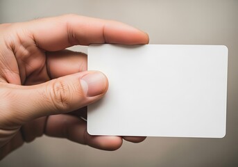 Fototapeta premium Hand holding a blank card against a soft background, perfect for showcasing a message