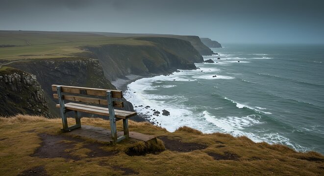 Coastal bench overlooking the ocean with green cliffs under overcast skies