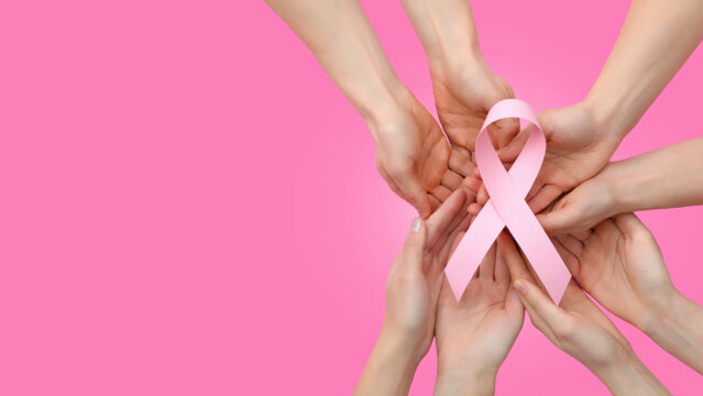 Hands hold a pink ribbon for cancer awareness