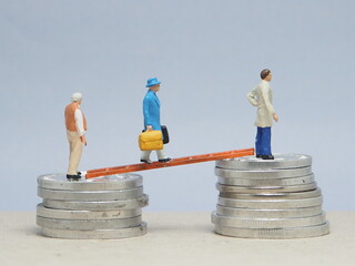 Mini toy of action figure at table with blurred background. Miniature photography concept design. Minifigure of businessman character walk on the money coin with ladder bridge.