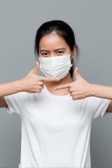 A woman wearing a mask poses, forming a frame with her hands, conveying a sense of focus and creativity.