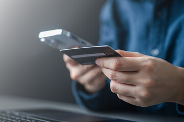 Close-up of hands holding credit card and smartphone, representing wallet top-up, adding funds,...