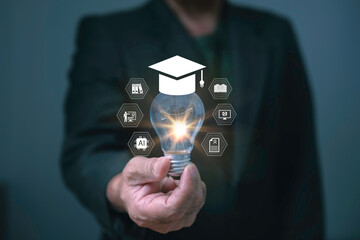 Businessman hand holding glowing light bulb with graduation cap and education icons, symbolizing knowledge, innovation, learning, artificial intelligence, and future digital education.