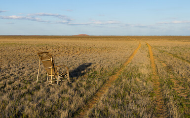Vintage creepy rocking chair next to a dirt path to nowhere in the outback of the Murchison region of Western Australia