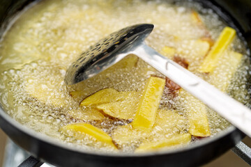 Potato wedges frying in hot oil for cooking process