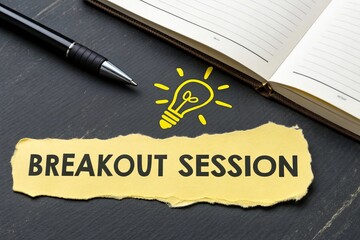Torn yellow paper spelling 'BREAKOUT SESSION' nearest with Light Bulb Icon arranged neatly on a dark desk, beside a book and a sleek pen for writing