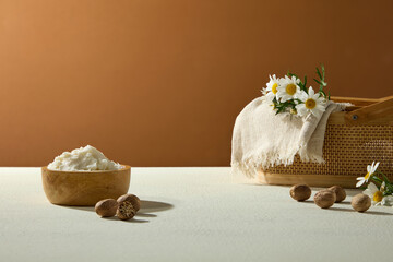 Shea butter blocks, nuts, and chamomile flowers arranged on warm brown background. A rustic still life for organic cosmetic visuals.