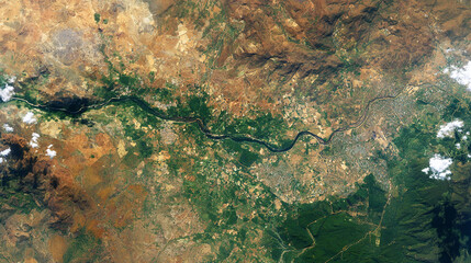 Fototapeta premium An aerial view from space shows a winding river separating a dry brown landscape from lush green areas dotted with towns and agricultural fields