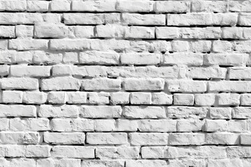 Obraz premium A textured white brick wall background with a rough and rustic appearance and deep shadows
