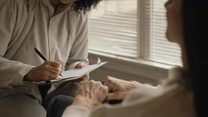 Therapist offering empathetic support, listening attentively while patient clasps hands in close-up, mental health care, counseling session, wellbeing