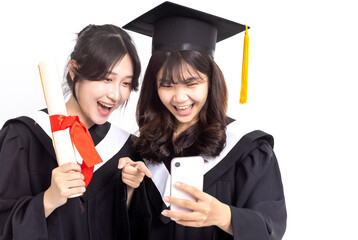 Happy Teenage girls wearing graduation gown and watching the smart phone