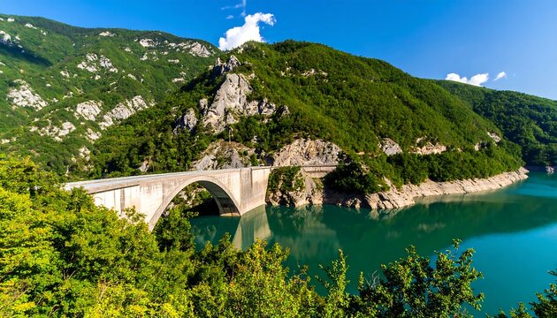 Scenic bridge spanning a tranquil lake nestled in lush green mountains
