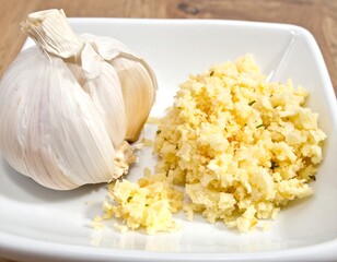 Whole garlic bulb and pile of minced garlic on a white square dish