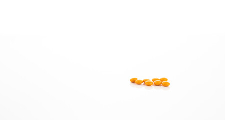 Prescription medicine yellow sugar coated tablet pills on white background representing pharmaceutical product healthcare innovation drug discovery and new clinical research in medical science.