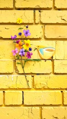 Yellow brick wall with colorful flowers and a small bird figurine