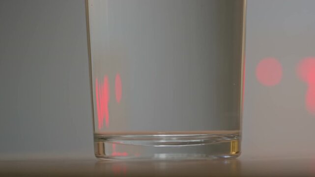 Close-up of hand of anonymous woman dropping effervescent tablet of vitamin or medication in glass of clear water, pill bubbling and fizzing while dissolving