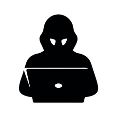 Silhouette of a hooded figure working on a laptop computer in the dark