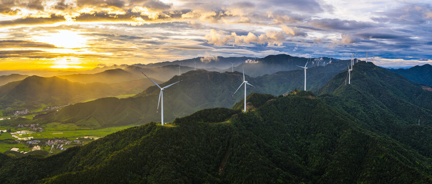 Panoramic view of wind turbines on the green mountains generating renewable electricity during a spectacular sunrise