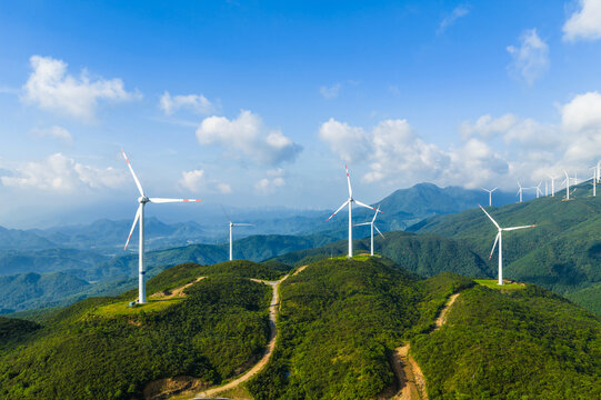 Aerial view of wind turbines on the green mountain generating clean and renewable energy on a sunny day - Powered by Adobe