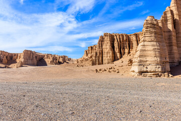 Desert gravel road ground and spectacular yardang landform mountain natural landscape in Xinjiang, China.