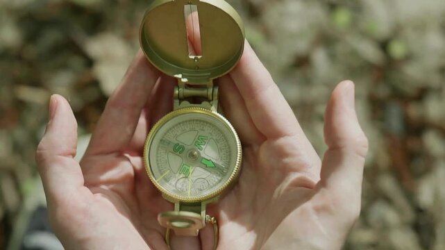 Man explorer searching direction with compass in summer mountains, point of view. compass for orienteering, hand holds magnetic compass, hike in the mountains, trekking alone, survival in the forest.