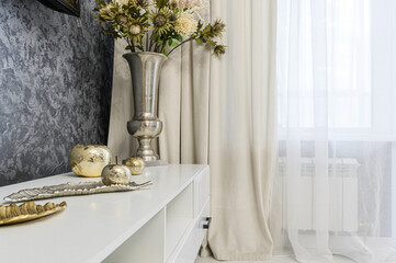 elegant interior featuring white sideboard adorned metallic accents: silver vase with flowers,...