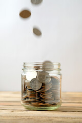 Income Stream and Savings Growth Concept with Coins Dropping into Glass Jar