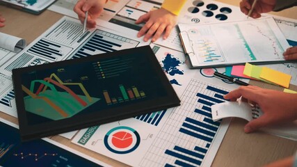 A diverse business team analyzes financial data in a modern office, using charts, graphs, and digital tools to discuss strategy and enhance decision-making processes. SACTR - Powered by Adobe