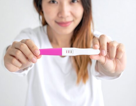 Close-up of a smiling woman displaying a positive pregnancy test - Powered by Adobe