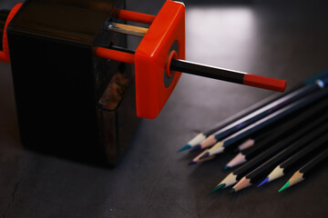Obraz na płótnie Canvas Electric Pencil Sharpener and Colored Pencils on Dark Desk Background