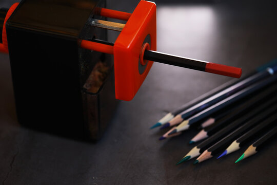 Electric Pencil Sharpener and Colored Pencils on Dark Desk Background