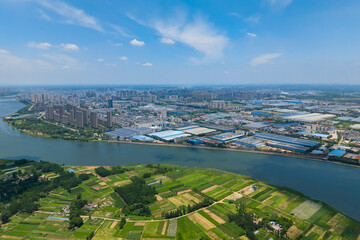 Fototapeta premium Suizhou City Hubei Province China shows a vast river meeting a city with green fields.