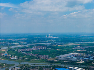 Suizhou City Hubei Province China vista shows cooling towers emitting steam under clouds in a wide...