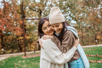 Fototapeta premium Mature daughter with older mom embracing in autumn park. Mother's day concept.