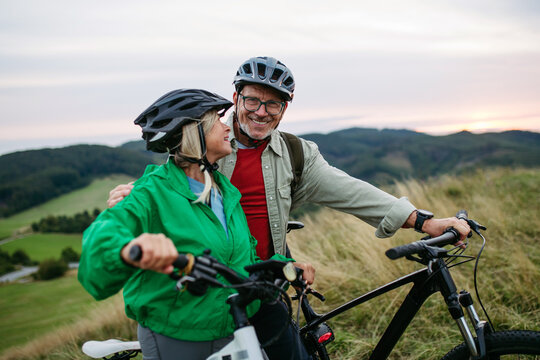 Older couple cycling together in nature, smiling and enjoying outdoor adventure.