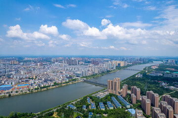 Suizhou City Hubei Province China shows a sprawling urban landscape with buildings and a river under a bright sky with clouds.