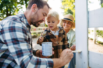 Little boy helping on farm, painting fence.