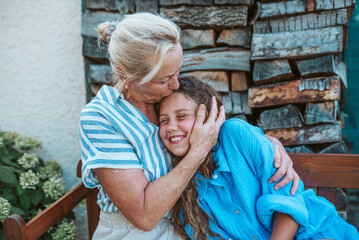 Grandmother and granddaughter hugging in the garden.