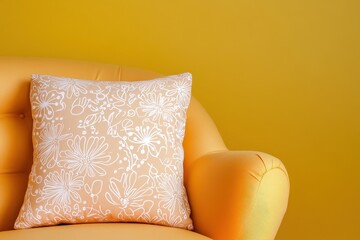 A decorative, cream-colored throw pillow with delicate floral designs rests on an orange armchair against a vibrant yellow backdrop.